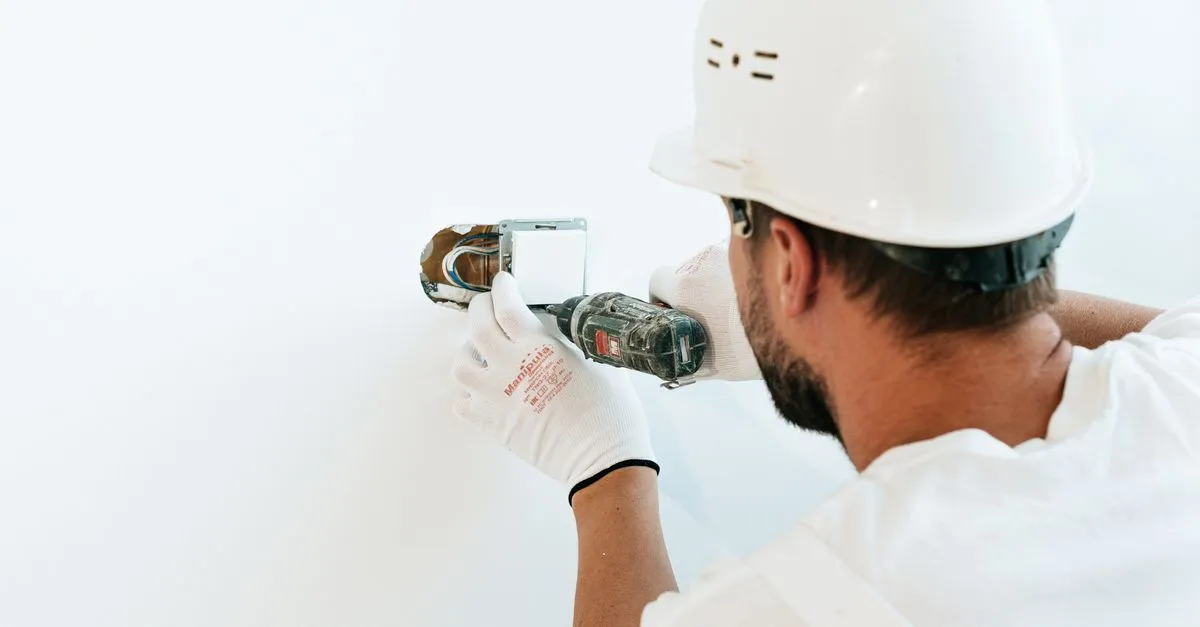 A professional drywall installer fastening a panel with a power tool